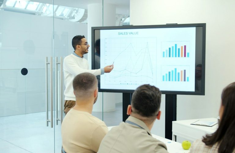 Laptop mit Datenanalysen auf dem Tisch, neben einer Tasse und Notizblöcken.